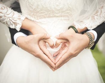 image of married couple making heart hands